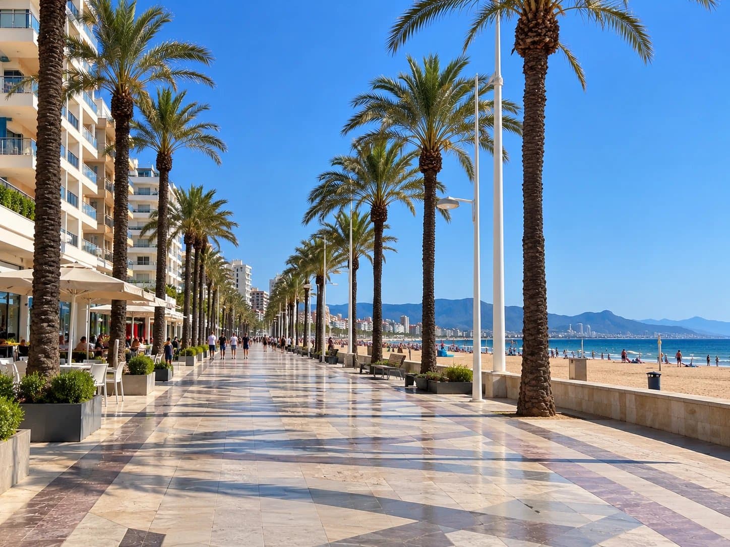 Paseo marítimo de la playa de Gandía, con palmeras y la arena al fondo